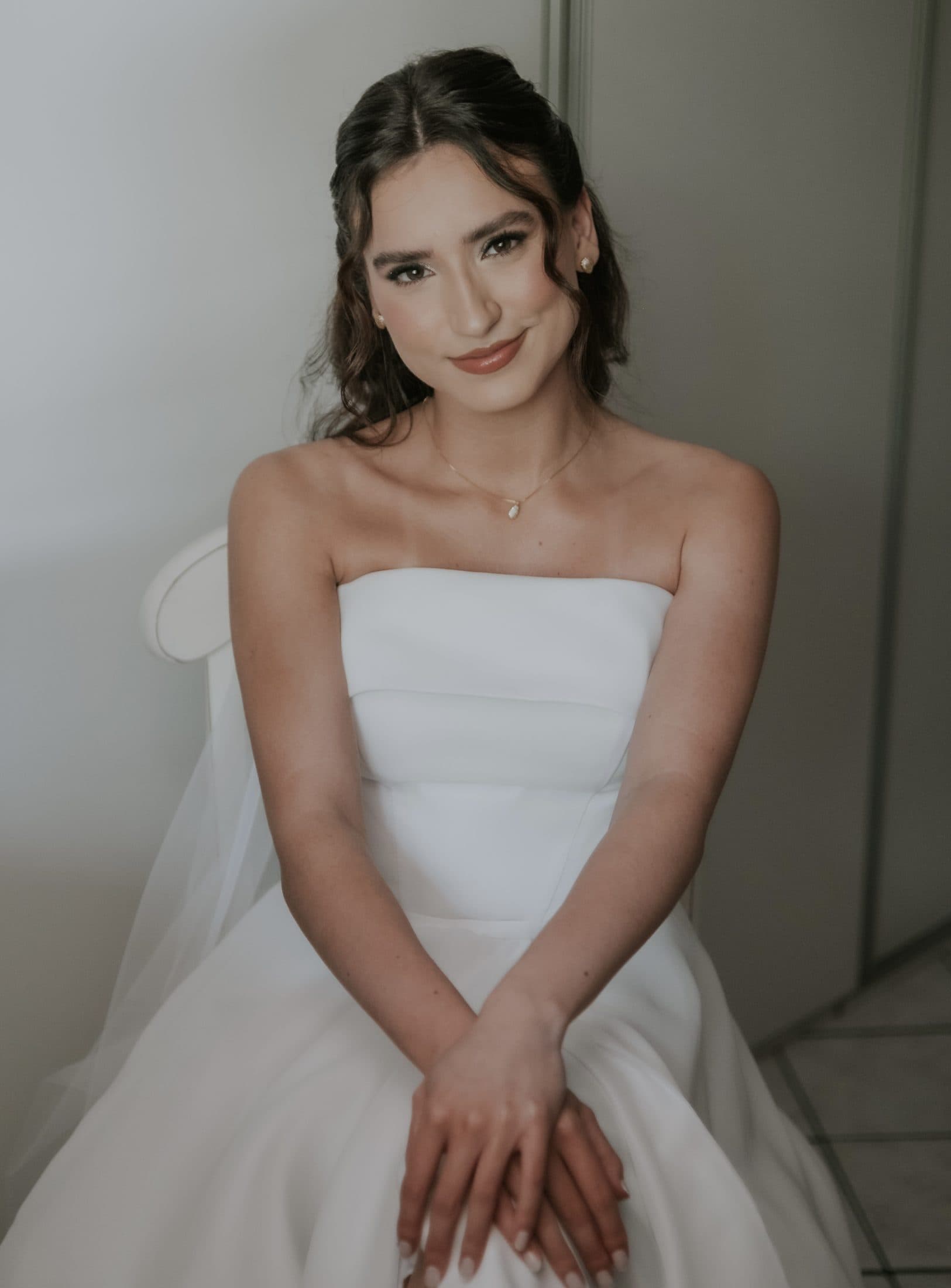 Noiva sentada com vestido tomara que caia e cabelo preso