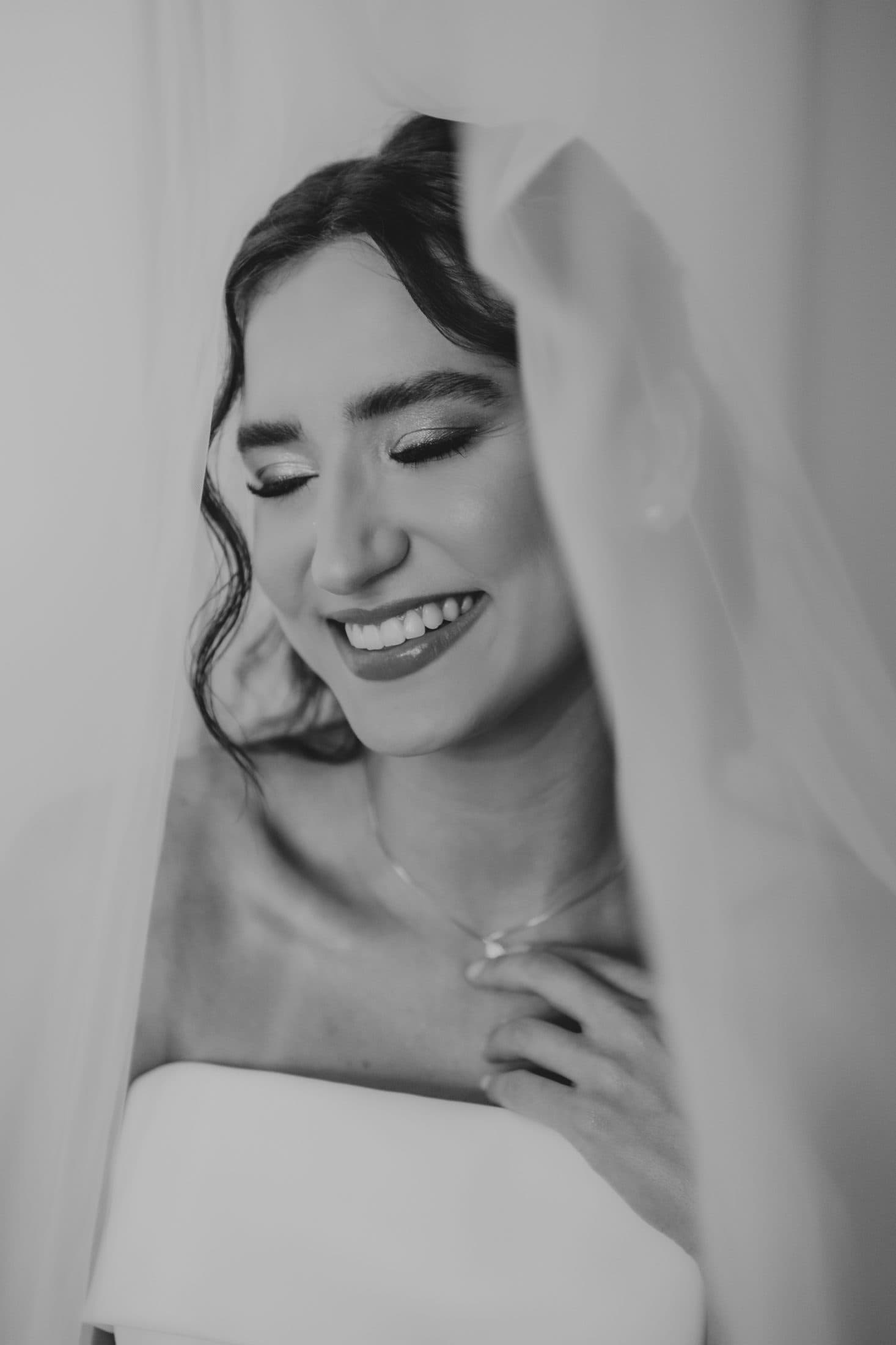 Retrato em preto e branco de noiva sorrindo sob o véu