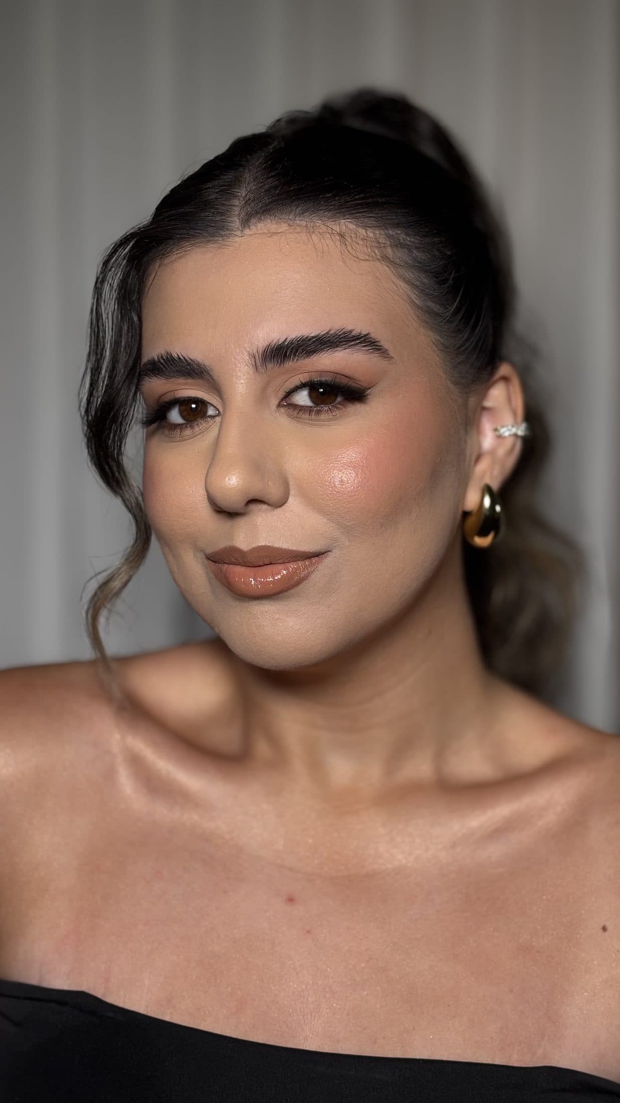 Maquiagem social com pele dourada e cabelo preso com mechas soltas