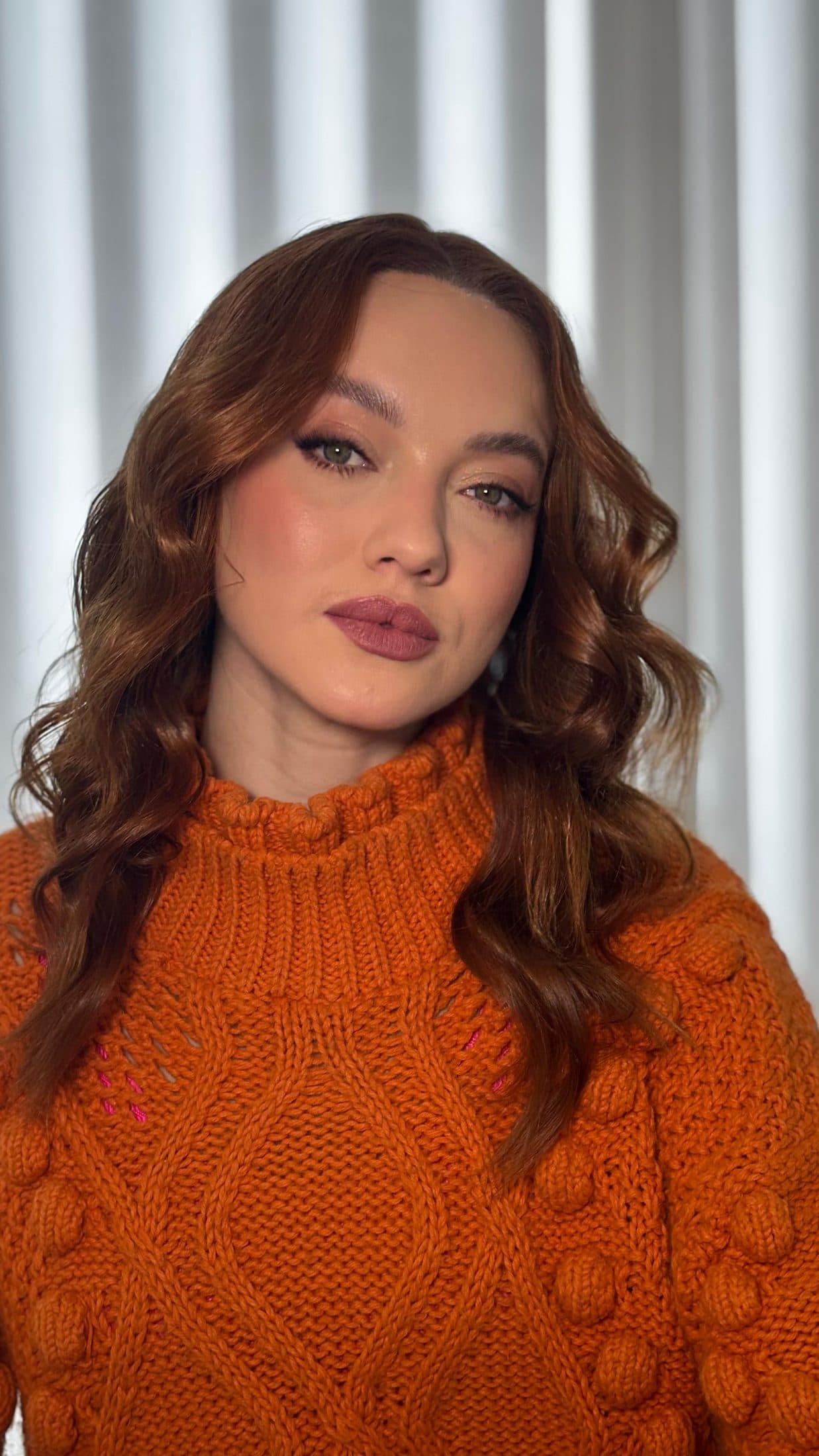 Maquiagem social em cliente ruiva com cabelo ondulado e suéter laranja
